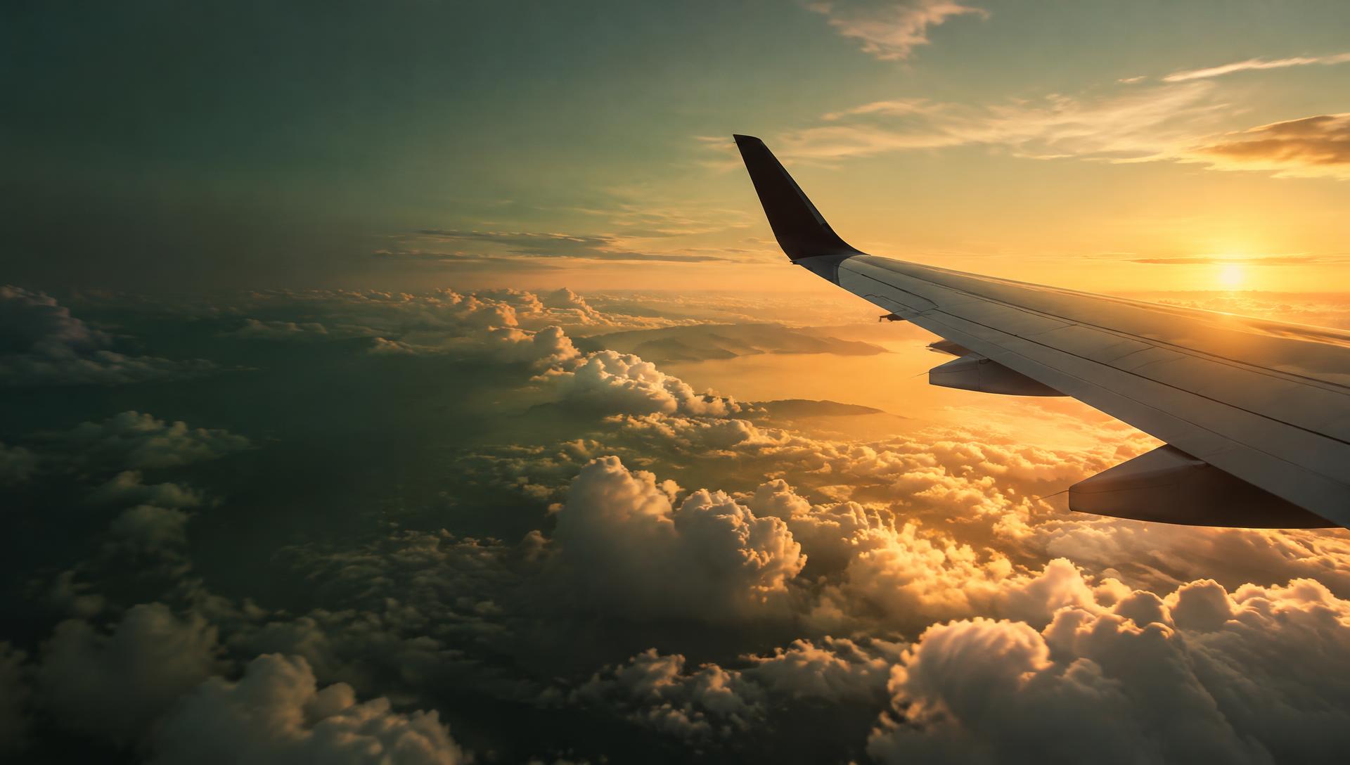 Asa de avião sobre nuvens douradas ao amanhecer